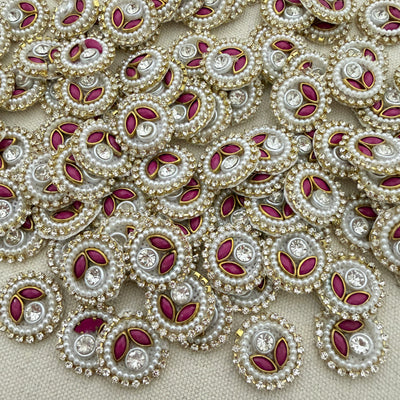 Close-up of decorative elements with pearls, red stones, and gold accents on a beige background