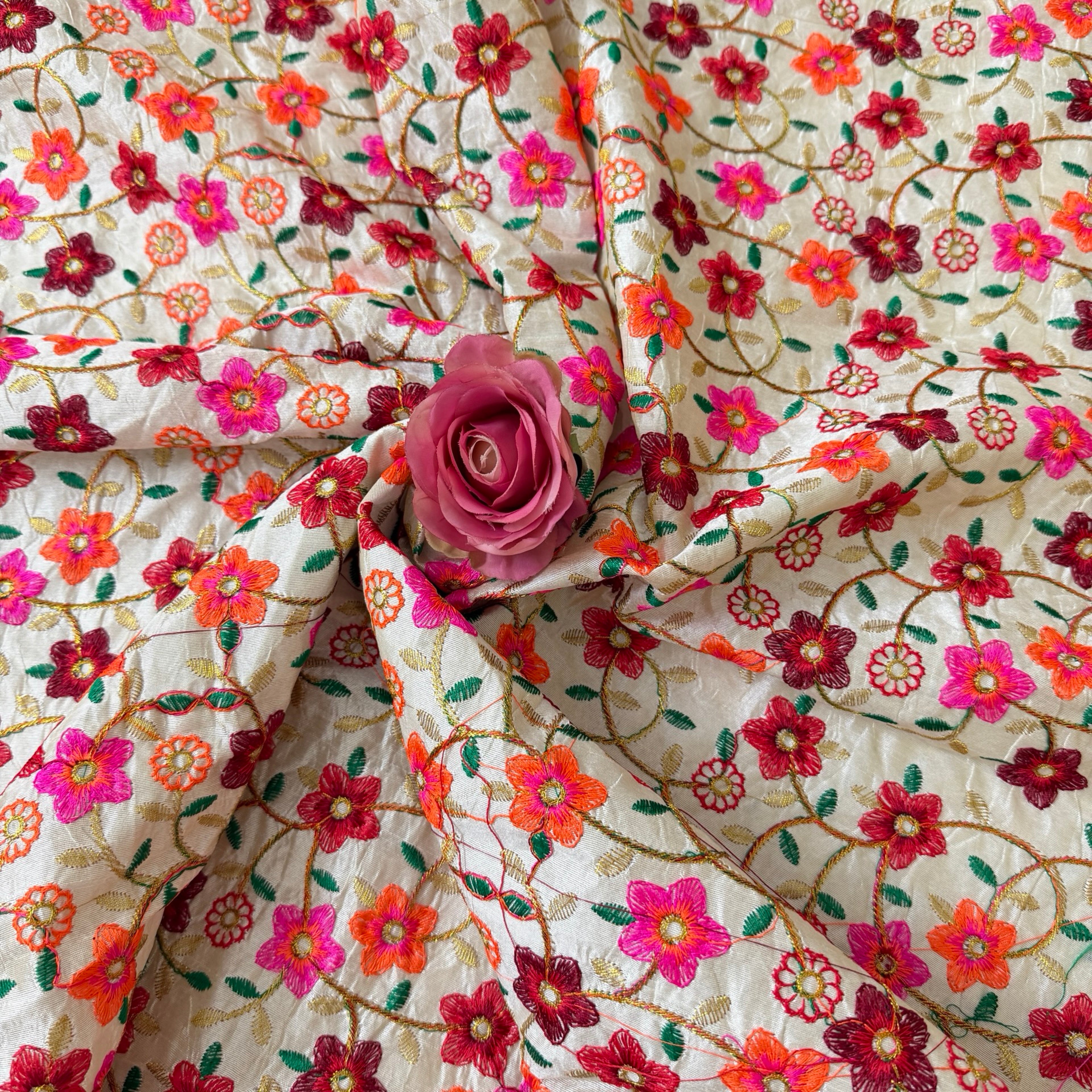 Floral embroidered fabric with a pink rose on top