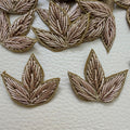 Close-up of a gold metallic three-leaf floral fabric patch