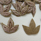 Gold three-leaf floral patch shown beside a ruler for size reference