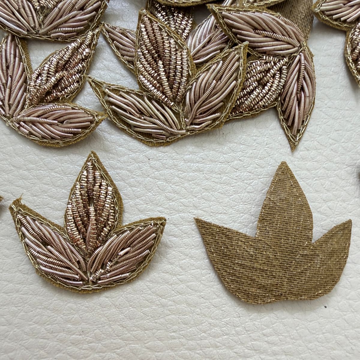 Gold three-leaf floral patch shown beside a ruler for size reference