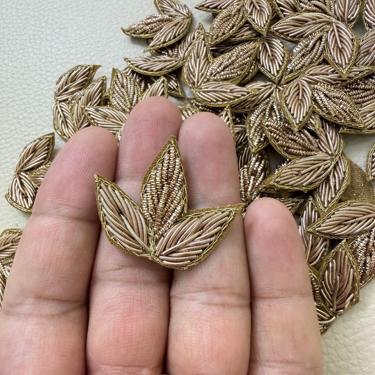 Multiple gold metallic floral leaf patches displayed on a light background