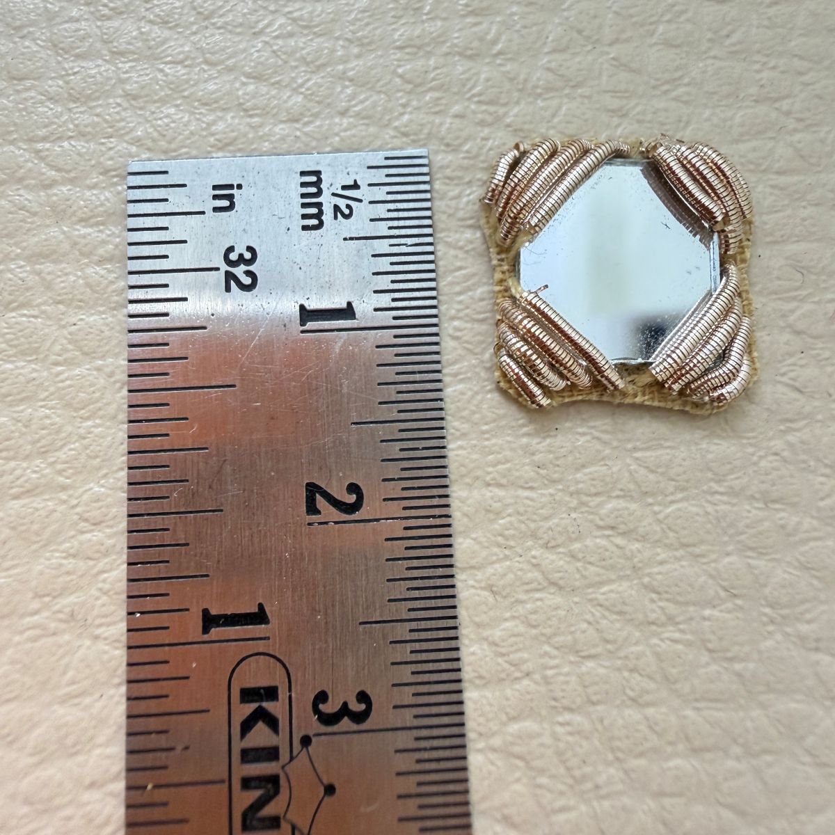 Antique gold square mirror applique patch beside ruler showing approximately 4 cm size