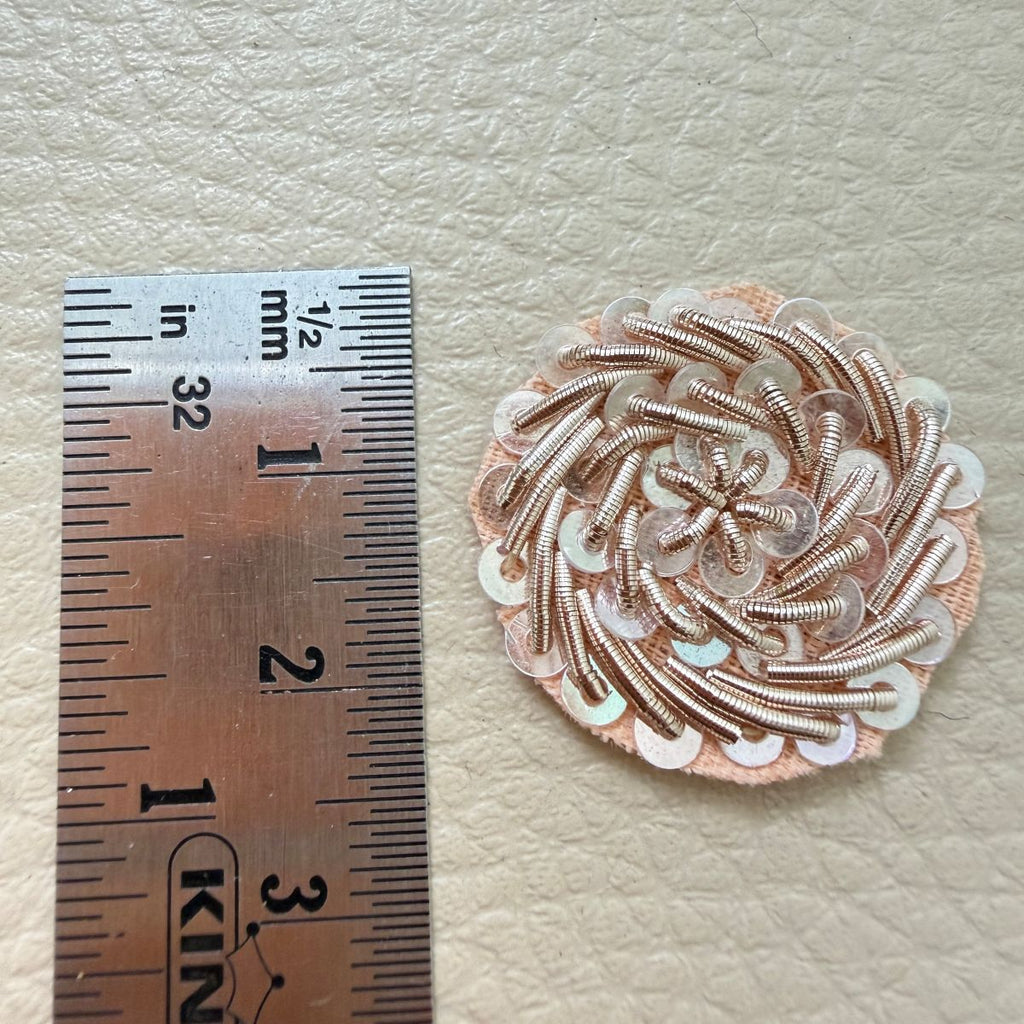 Small round rose gold metallic coil and sequin floral patch shown in hand for scale