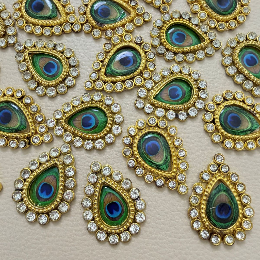 Front and mesh back of gold-tone teardrop patch with peacock-eye center and clear rhinestones