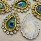 Close-up of two green and blue peacock-eye teardrop patches with clear rhinestone borders