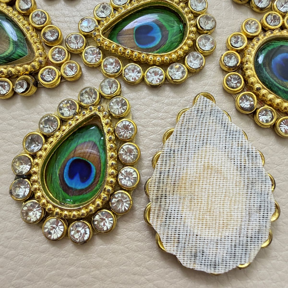 Close-up of two green and blue peacock-eye teardrop patches with clear rhinestone borders