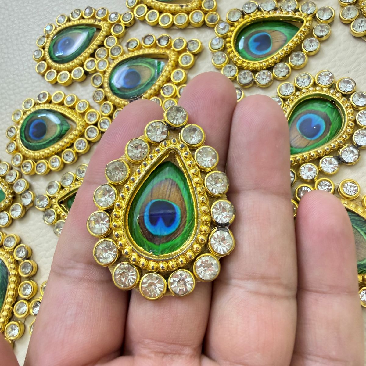 Multiple gold-tone teardrop patches with peacock-eye centers and clear rhinestones