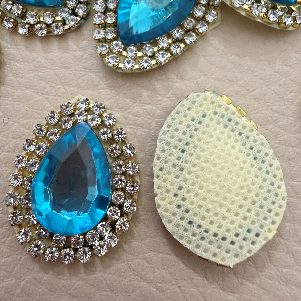 Aqua blue teardrop rhinestone patch shown in hand for scale
