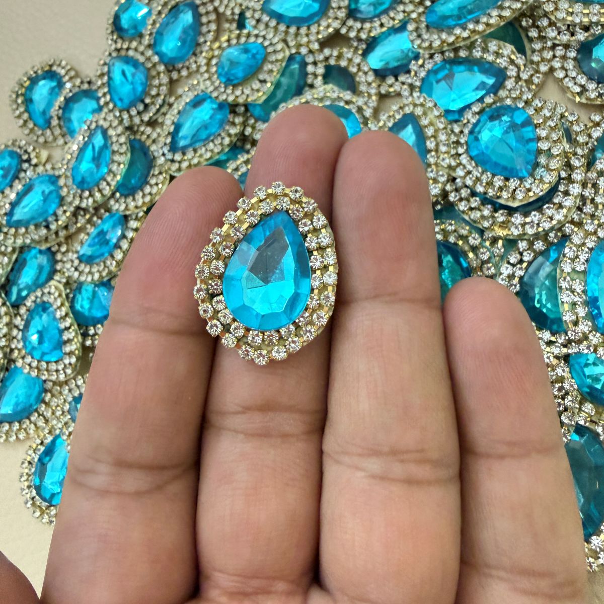 Aqua blue teardrop crystal rhinestone patch beside ruler showing approximate size
