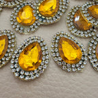 Close-up of amber gold faceted teardrop stone and clear rhinestone border