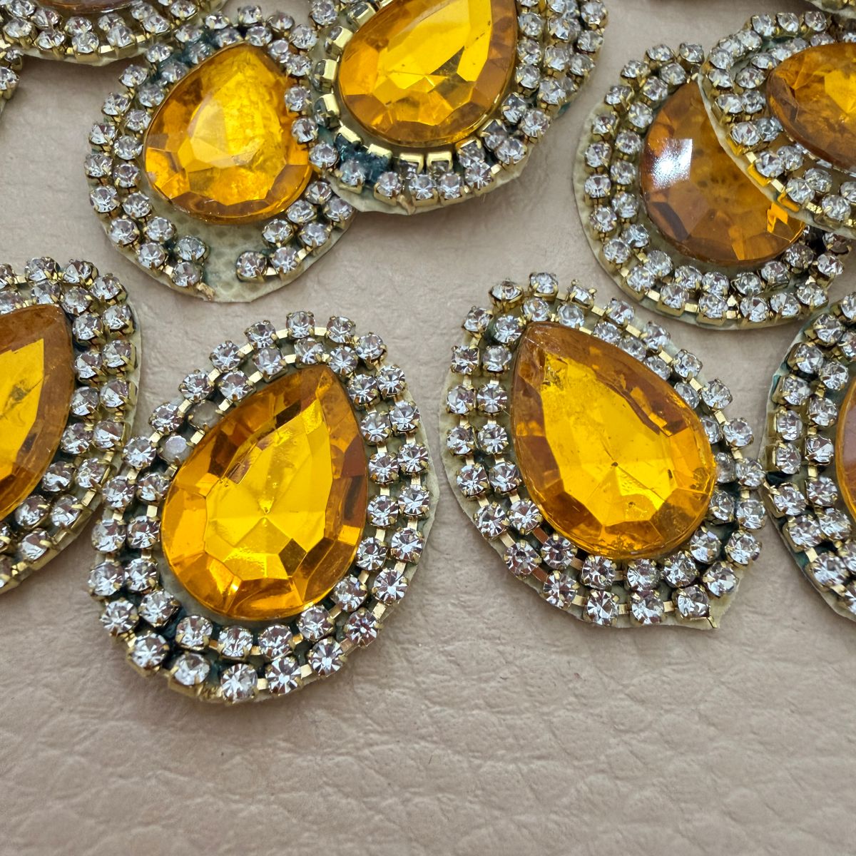 Close-up of amber gold faceted teardrop stone and clear rhinestone border