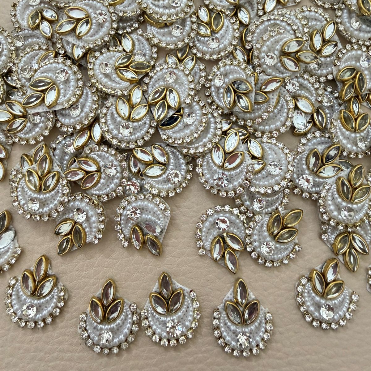 White crescent patch with layered pearl-like beads, clear rhinestones, center crystal, and gold marquise accents