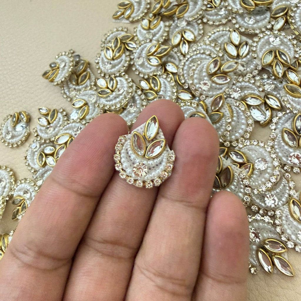 Multiple white pearl-look crescent patches with gold marquise accents and rhinestone borders