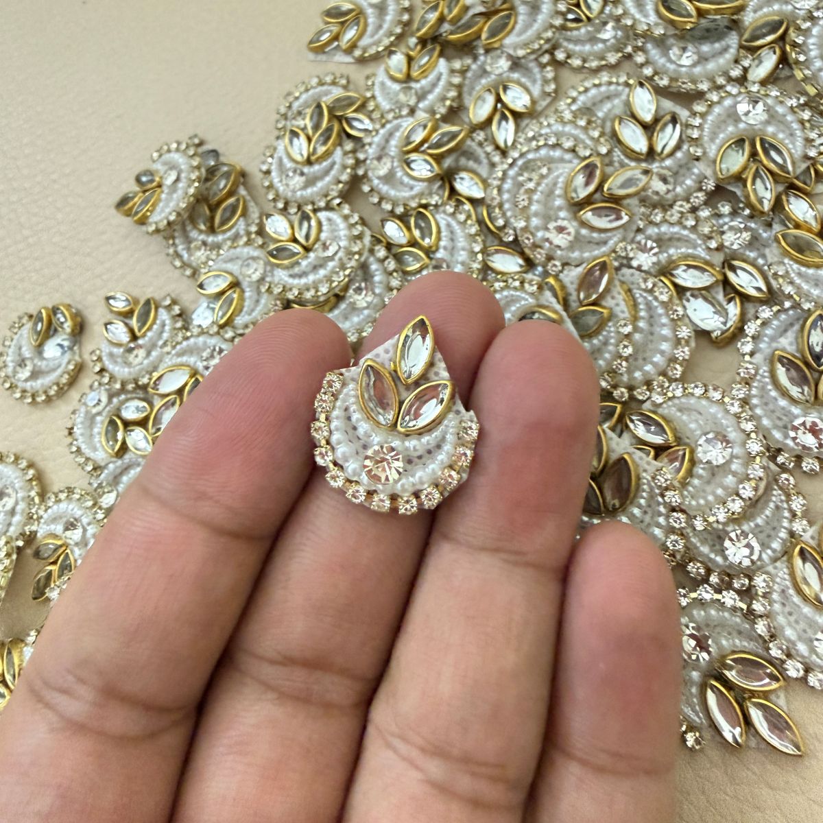 Multiple white pearl-look crescent patches with gold marquise accents and rhinestone borders