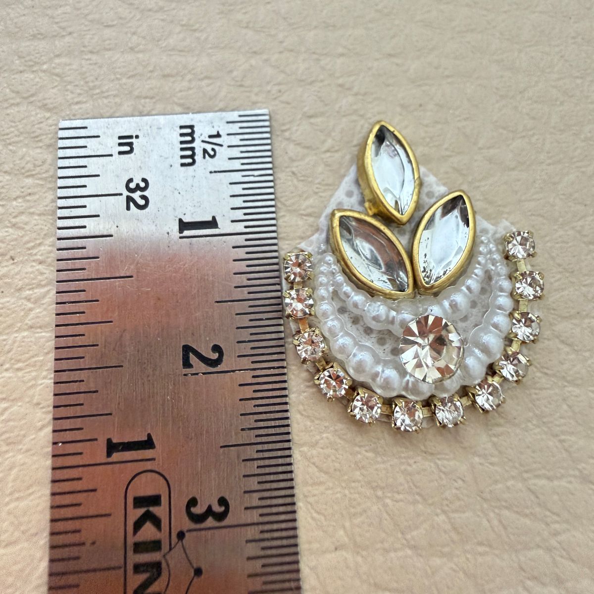 Close view of two white beaded crescent patches with crystal centers and gold-tone accents