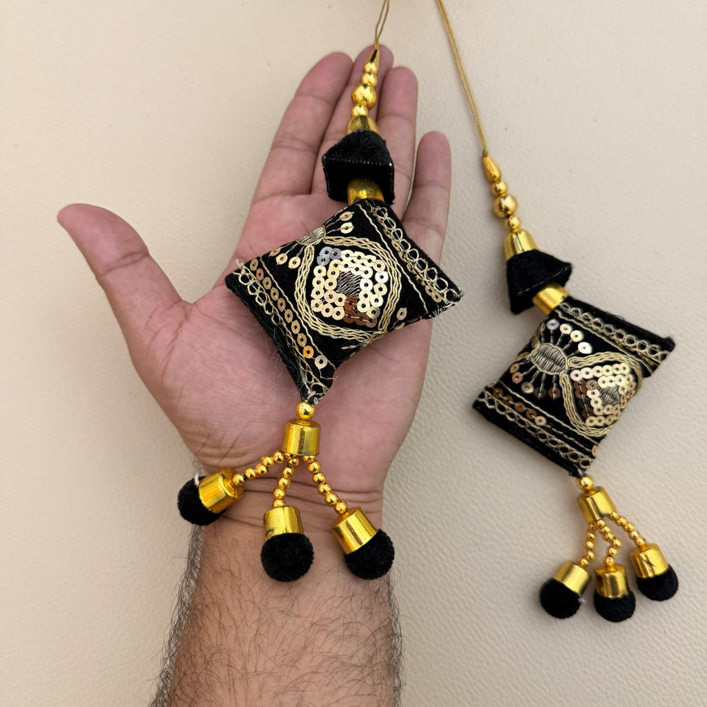 Multiple black and gold decorative tassels showing embroidered sequin motifs and beadwork