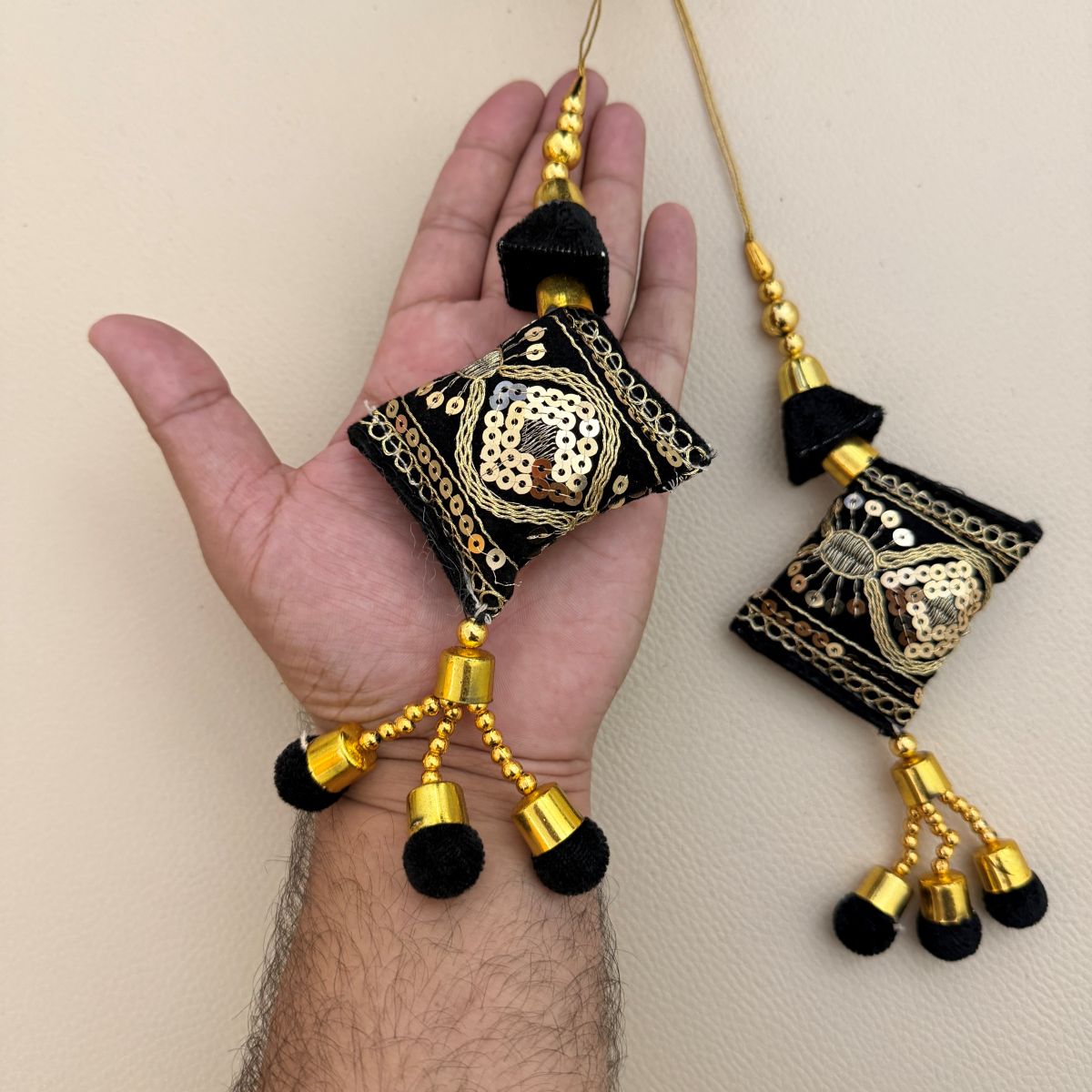 Multiple black and gold decorative tassels showing embroidered sequin motifs and beadwork