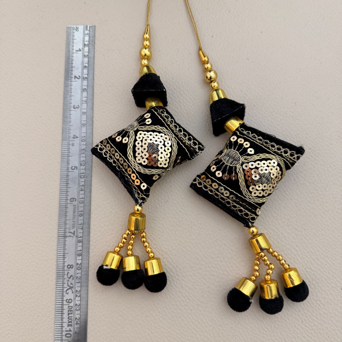 Pair of black textile tassels with gold sequins, bead accents, and ornamental details