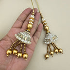 Two gold and silver pearl latkan tassels shown in hand for scale