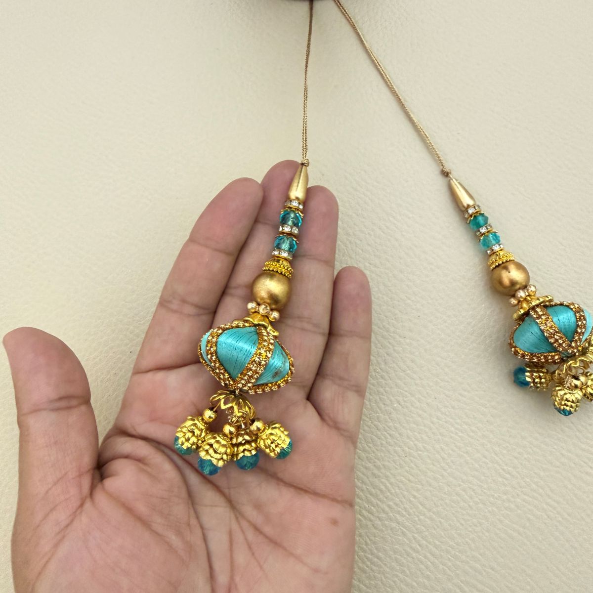 Matching turquoise thread and gold beaded latkan tassels with rhinestone trim