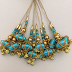 Hand holding turquoise and antique gold beaded latkan tassel to show scale