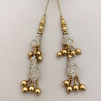 Two gold and silver embroidered tassel latkans beside a ruler