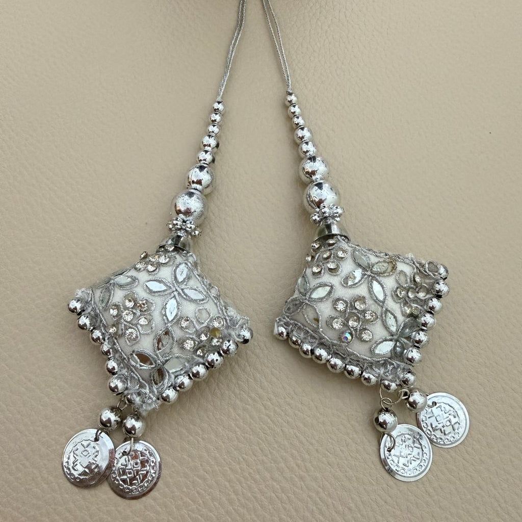 Pair of silver square latkan tassels with floral embroidery, beads and coin charms shown beside a ruler