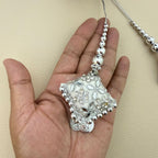Close-up of one silver embroidered square latkan tassel with beaded cord shown in hand