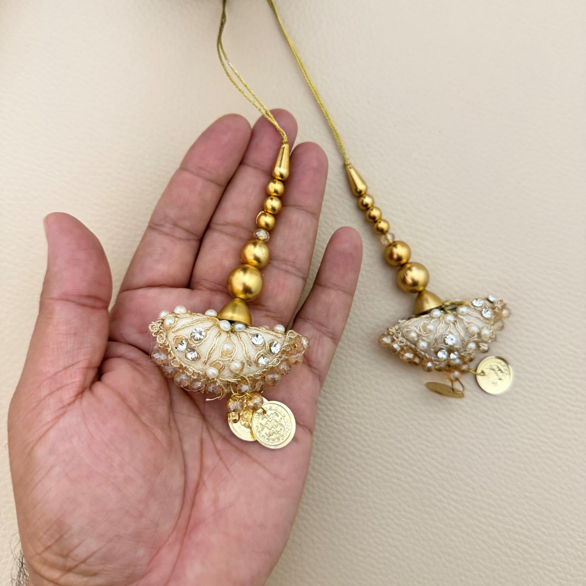 Ivory gold decorative latkan tassels beside a metric ruler showing approximate size
