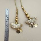 Close view of ivory fan-shaped tassels with gold embroidery, pearl beads, crystals and coin charms