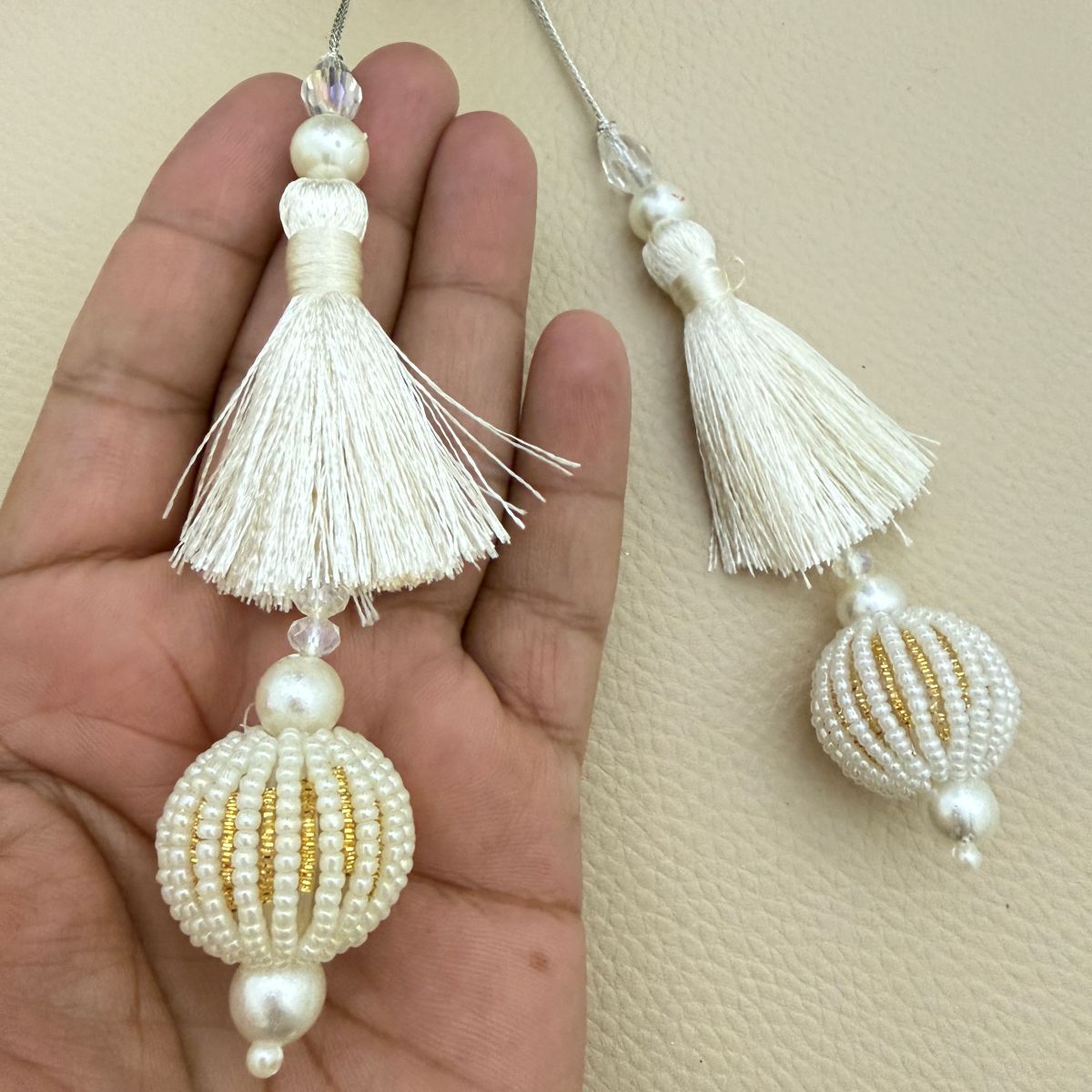 Ivory pearl and gold beaded tassels beside a ruler showing approximate decorative length