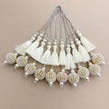 Close-up of ivory thread fringe, pearl-look beads, clear crystals and gold striped seed-bead ball