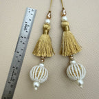 Two gold fringe tassels with white and gold striped beaded balls and pearl-look accents
