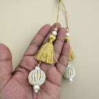 Gold thread and white beaded ball latkan tassels shown in hand for scale