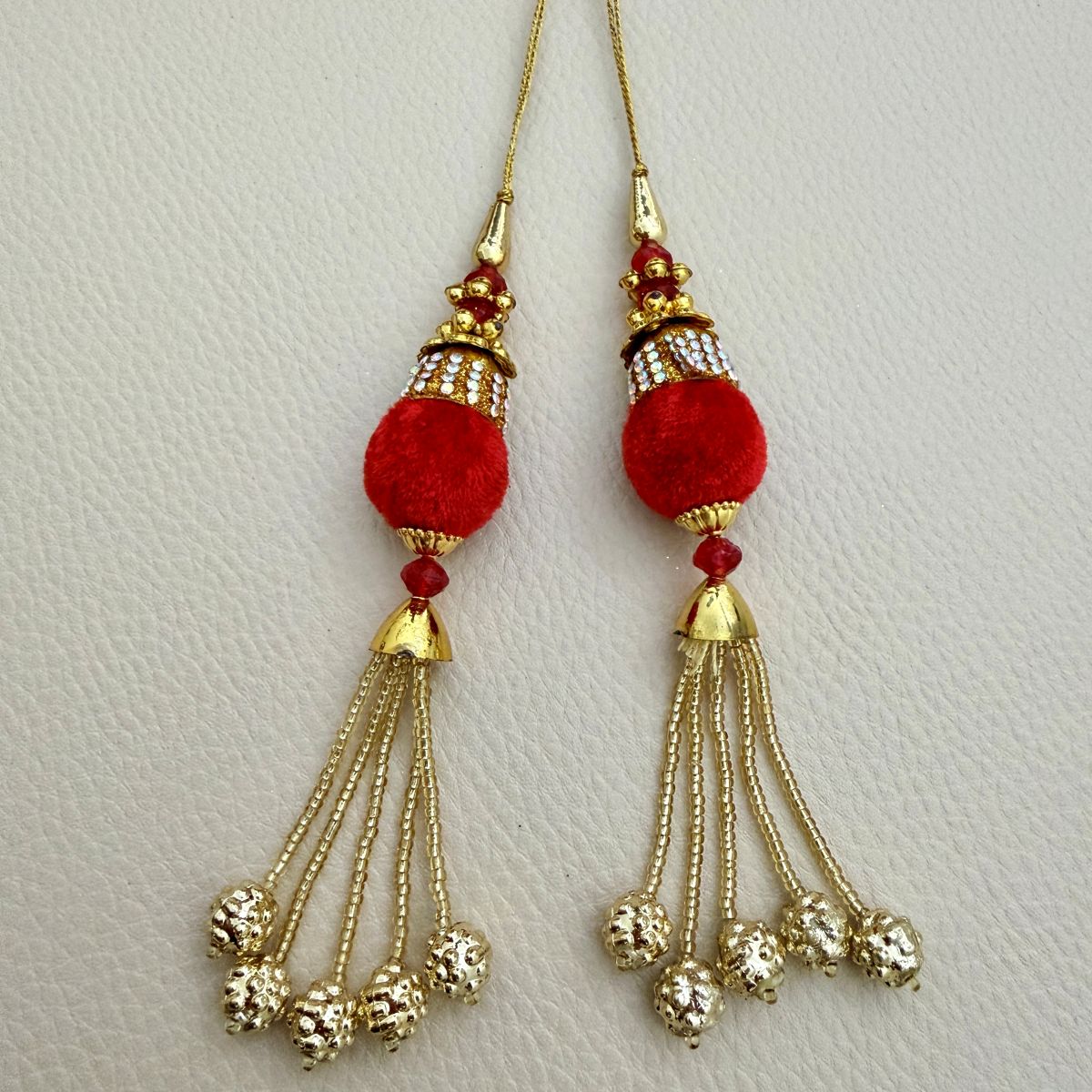 Pair of red textured ball latkan tassels with gold chain fringe and ornate bead tips