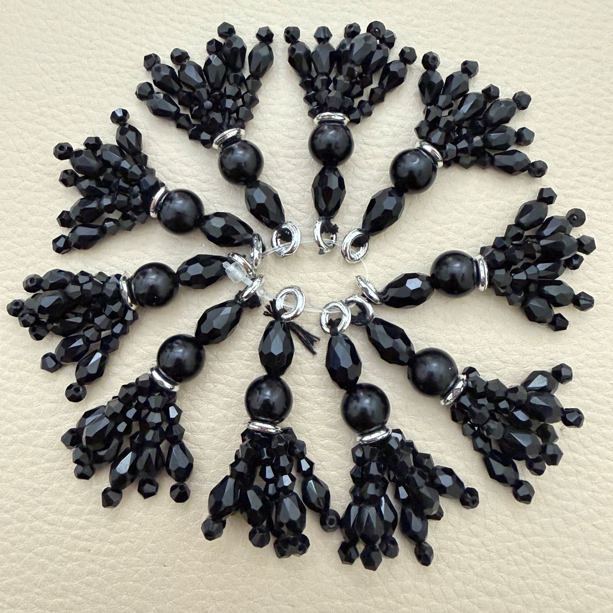 Ten black faceted beaded tassel charms arranged in a circle