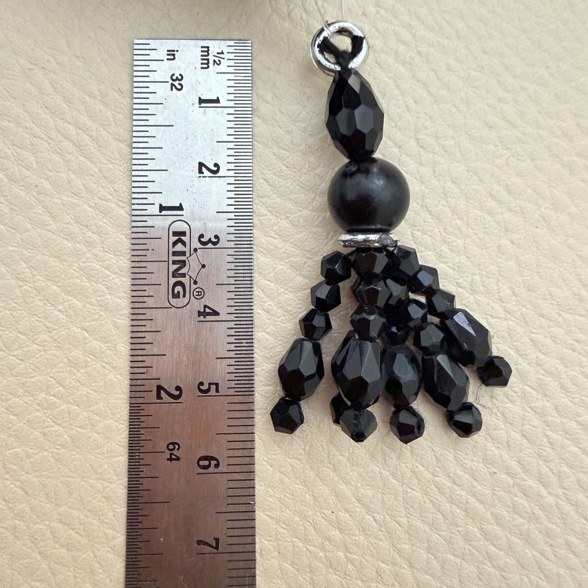 Close-up of a black faceted beaded tassel charm with silver-tone rings