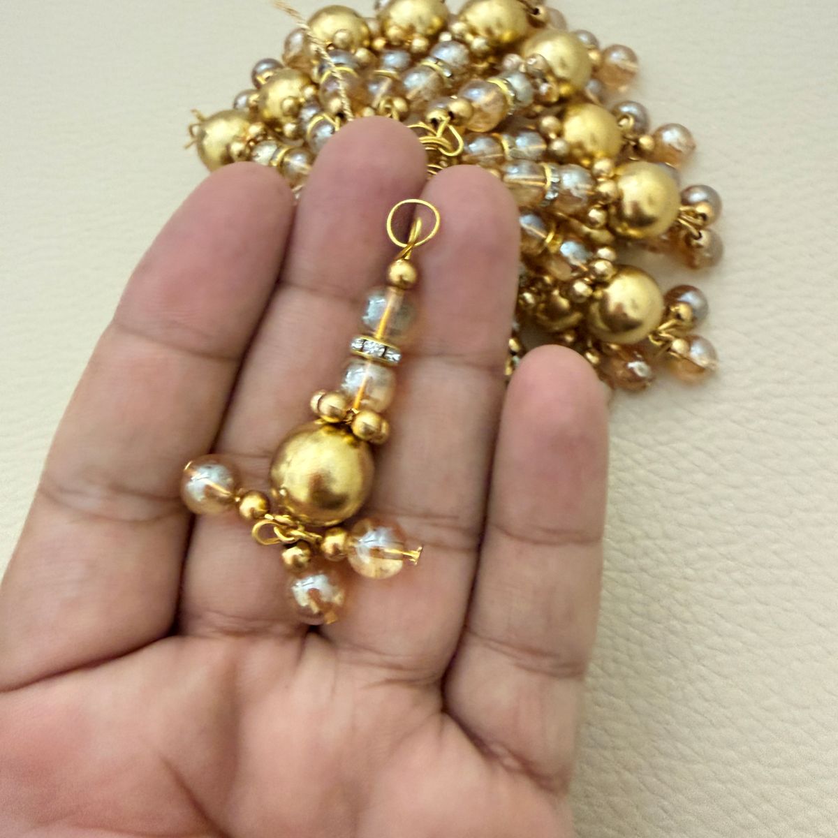 Gold tone beaded latkan shown beside a ruler for approximate scale