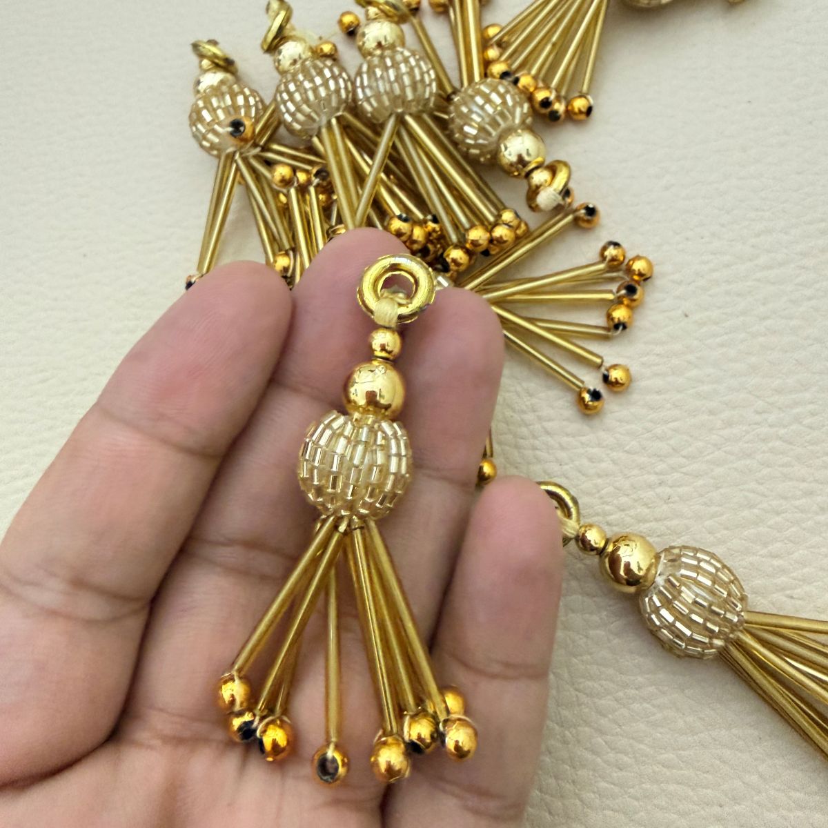 Pair of gold-tone tassel charms with circular loops, bugle-bead centers, and ball-tipped drops