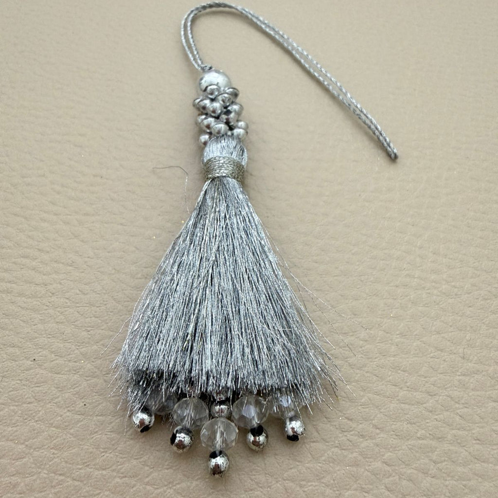 Silver silk tassel with beaded cap held in hand for scale