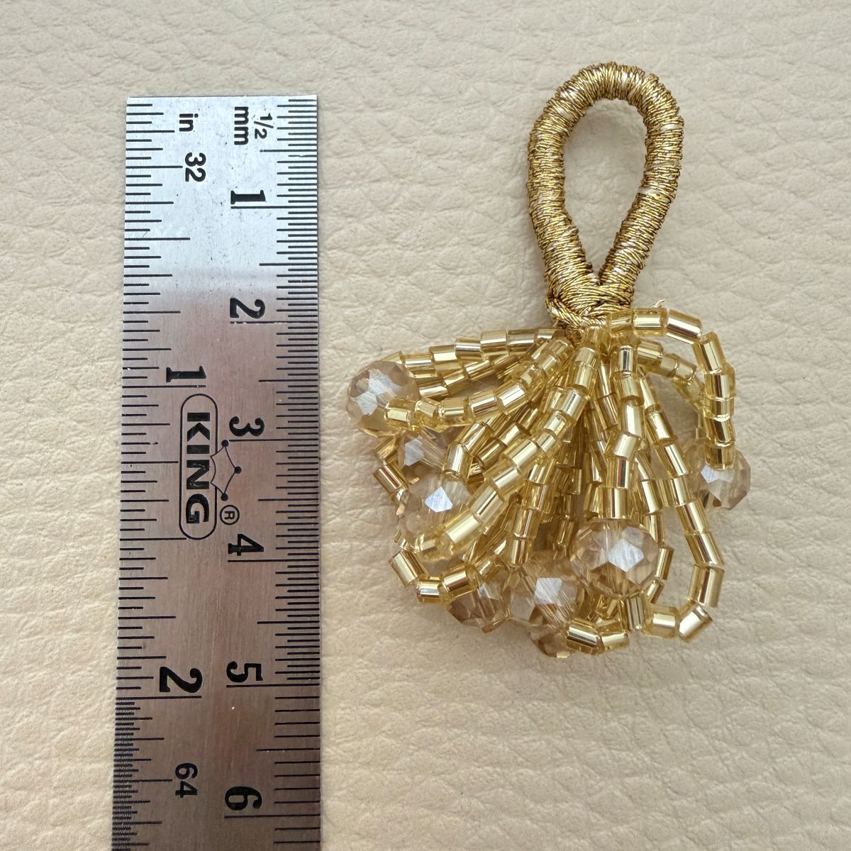 Gold crystal bead bunch latkan shown beside a ruler for size reference