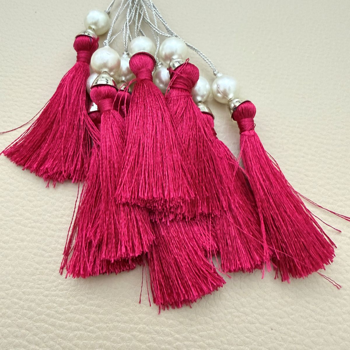 Group of fuchsia pink tassels with pearl-style beads and metallic caps