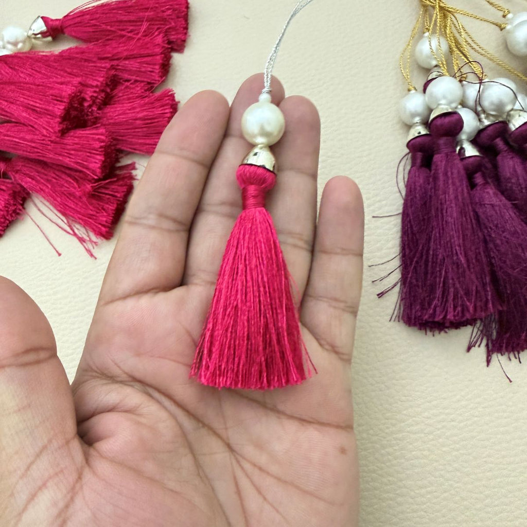 Fuchsia pink tassel shown in hand to illustrate its compact lightweight size