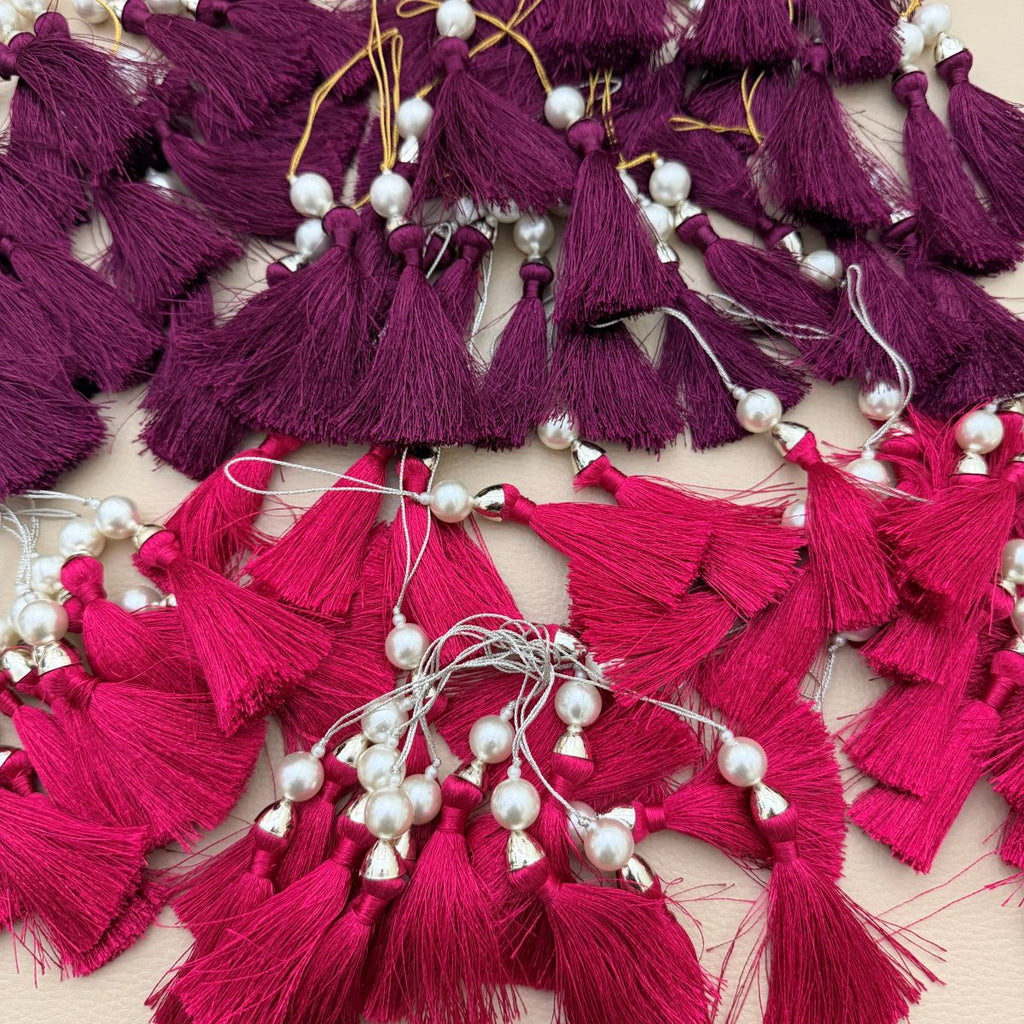 Single fuchsia pink tassel with pearl-style bead, metallic cap, and hanging loop