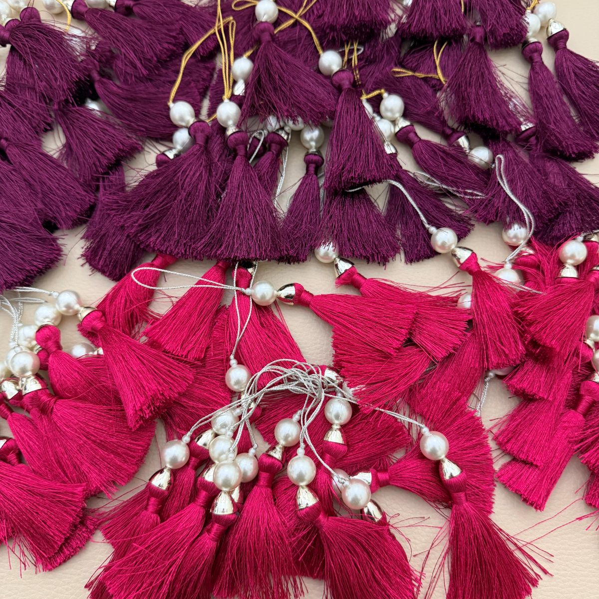 Single fuchsia pink tassel with pearl-style bead, metallic cap, and hanging loop