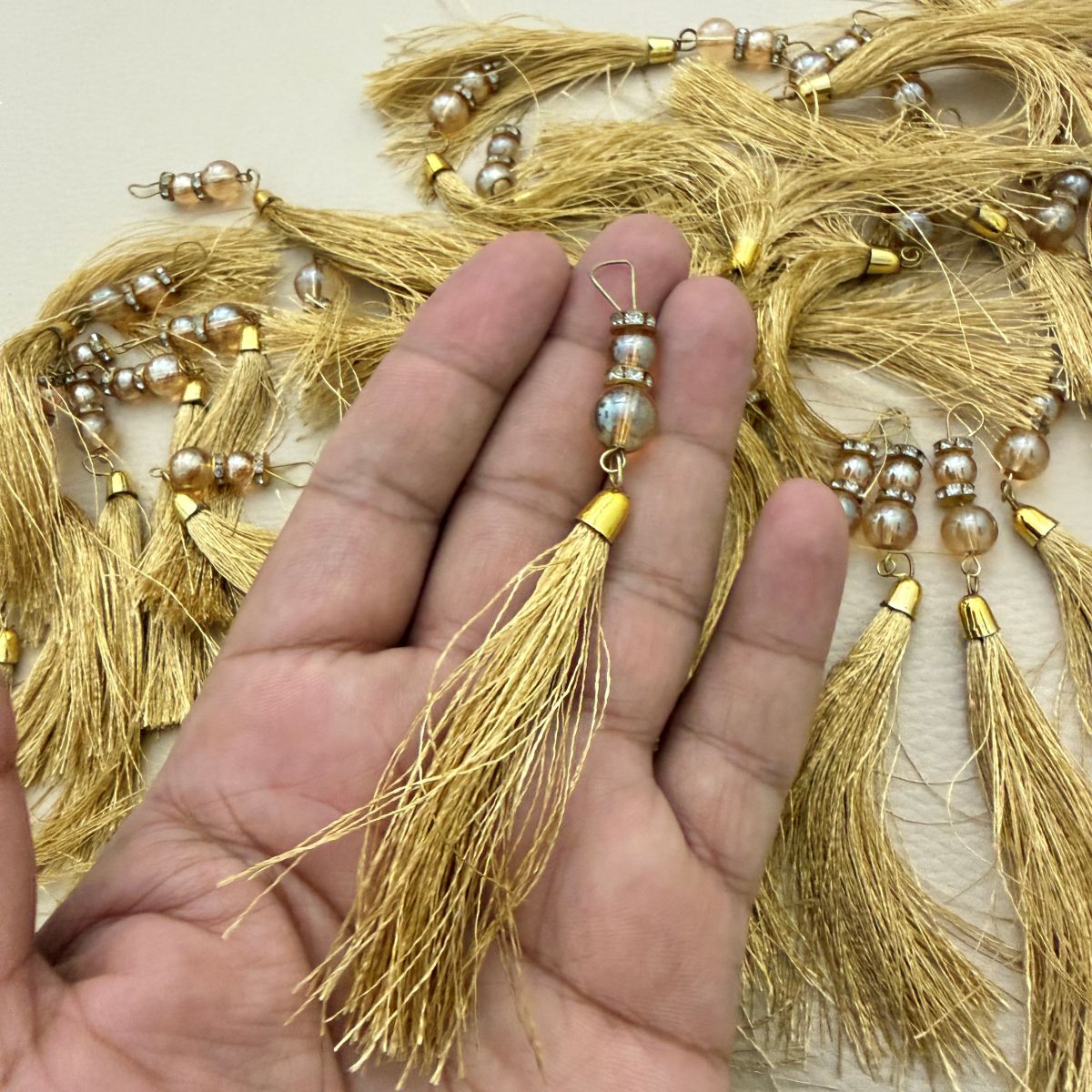 Close view of gold tassel threadwork, beaded accent, and metal cap