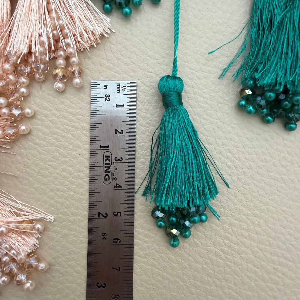 Teal green and blush peach beaded tassels with hand for scale