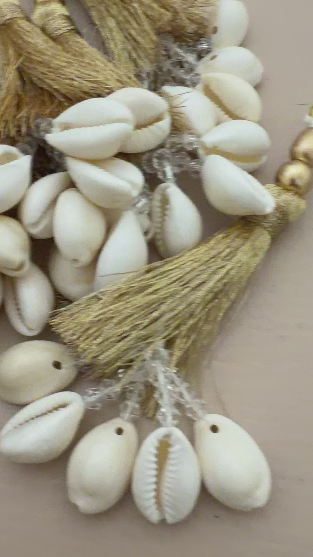 Decorative keychain with tassels and cowrie shells on a beige background
