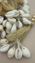 Decorative keychain with tassels and cowrie shells on a beige background